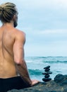 Balancing stones arranged in a pyramid shape with a back of a shirtless man meditating Royalty Free Stock Photo