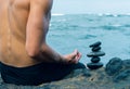 Balancing stones arranged in a pyramid shape with a back of a shirtless man meditating Royalty Free Stock Photo