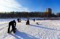 People sledding down the riverbank of the Pekhorka river on a sunny winter day. City of Balashikha, Moscow region, Russia