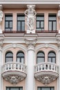 Balconies with windows, figures of Atlanteans and columns decorated with stucco, details of the facade of an old building Royalty Free Stock Photo