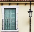 Balcony with green doors and classic lamppost on yellow facade