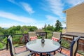 Balcony house exterior with glass railings, table set and perfect view.