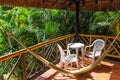 Balcony with table chairs and hammock against the background of tropical greenery on a sunny day Royalty Free Stock Photo