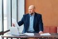 Bald adult businessman beard working doing paperwork,sitting wooden desk laptop