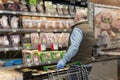 A bald adult man in a medical mask chooses chilled meat products in a supermarket. Healthy eating Back view. Self-isolation during