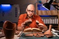 Bald archaeologist working at night in the office studying ancient artifacts. Royalty Free Stock Photo