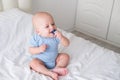 bald baby boy 3 months in blue bodysuit playing with children wooden cubes toys on bed Royalty Free Stock Photo