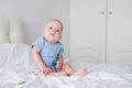 bald baby boy 3 months in blue bodysuit playing with children wooden cubes toys on bed Royalty Free Stock Photo