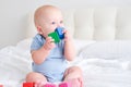 bald baby boy 3 months in blue bodysuit playing with children wooden cubes toys on bed Royalty Free Stock Photo