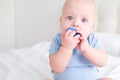 bald baby boy 3 months in blue bodysuit playing with children wooden cubes toys on bed Royalty Free Stock Photo