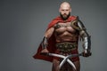 Bald and bearded gladiator poses standing tall with two swords Royalty Free Stock Photo