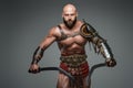 Bald and bearded gladiator poses standing tall with two swords Royalty Free Stock Photo