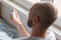 A bald, bearded man holds an inhaler in his hand and lying in bed. Top view, from the back. The concept of World Asthma Royalty Free Stock Photo