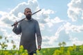 Bald bearded man in metal chain mail over linen shirt stands in the middle of field, holding a sword. Militant look. Blurred