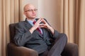 Bald businessman in glasses sitting in a chair in a hotel. Royalty Free Stock Photo