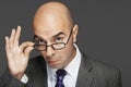 Bald Businessman With Hand On Glasses Making A Face