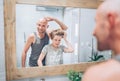 Bald dad and his long-haired teenager son in bathroom in front of the mirror. Father showing to boy his new style haircut. Common Royalty Free Stock Photo