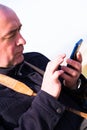 Portrait of bald elderly man looking at smartphone