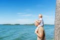 Bald father and cute kid sitting on shoulders looking blue sea