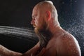 The bald guy takes a shower. A brutal man with a red beard is standing in the bathroom under a stream of water and