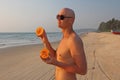 A bald and handsome man with a or bare torso eats a melon
