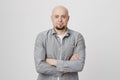 Bald handsome man with beard and crossed hands standing over white background. Person in casual clothes waiting in queue