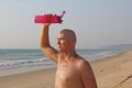 A bald, handsome man with a naked or bare torso watering himself with water from a pink fitness bottle. The man is thirsty. Heat Royalty Free Stock Photo