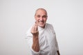 Bald handsome mature man looking angry showing italian gesture over white background.