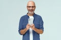Bald handsome middle aged man holding smartphone in hand excited looking at it reading text or browsing social media Royalty Free Stock Photo
