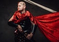 Hairless roman warrior pose with red cape in dark background