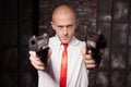 Bald hired killer in red tie aims a pistols Royalty Free Stock Photo