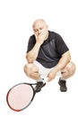 A bald man in an adult in a sports uniform with a tennis racket sits tired. Full height. Isolated over white background. Royalty Free Stock Photo