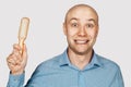 Bald man with alopecia holds a comb in his hand. concept absurdity