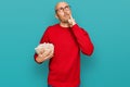 Bald man with beard eating popcorn serious face thinking about question with hand on chin, thoughtful about confusing idea Royalty Free Stock Photo