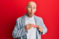 Bald man with beard holding broken heart paper shape afraid and shocked with surprise and amazed expression, fear and excited face Royalty Free Stock Photo