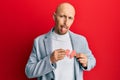 Bald man with beard holding broken heart paper shape sticking tongue out happy with funny expression Royalty Free Stock Photo