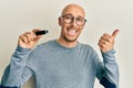 Bald man with beard holding removable memory usb pointing thumb up to the side smiling happy with open mouth Royalty Free Stock Photo
