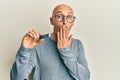 Bald man with beard holding ssd memory covering mouth with hand, shocked and afraid for mistake Royalty Free Stock Photo