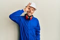 Bald man with beard wearing builder jumpsuit uniform and hardhat smiling happy doing ok sign with hand on eye looking through Royalty Free Stock Photo