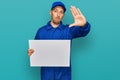 Bald man with beard wearing builder jumpsuit uniform holding empty banner with open hand doing stop sign with serious and Royalty Free Stock Photo