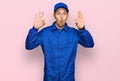 Bald man with beard wearing builder jumpsuit uniform looking surprised and shocked doing ok approval symbol with fingers