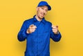 Bald man with beard wearing builder jumpsuit uniform pointing fingers to camera with happy and funny face Royalty Free Stock Photo