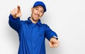 Bald man with beard wearing builder jumpsuit uniform pointing to you and the camera with fingers, smiling positive and cheerful Royalty Free Stock Photo