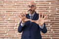 Bald man with beard wearing business clothes and glasses afraid and terrified with fear expression stop gesture with hands, Royalty Free Stock Photo