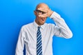 Bald man with beard wearing business clothes and glasses peeking in shock covering face and eyes with hand, looking through Royalty Free Stock Photo
