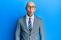 Bald man with beard wearing business jacket and glasses scared and amazed with open mouth for surprise, disbelief face Royalty Free Stock Photo