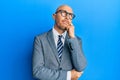 Bald man with beard wearing business jacket and glasses serious face thinking about question with hand on chin, thoughtful about Royalty Free Stock Photo