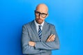 Bald man with beard wearing business jacket and glasses skeptic and nervous, disapproving expression on face with crossed arms Royalty Free Stock Photo