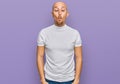 Bald man with beard wearing casual white t shirt making fish face with lips, crazy and comical gesture