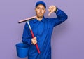 Bald man with beard wearing glass cleaner uniform and squeegee with angry face, negative sign showing dislike with thumbs down, Royalty Free Stock Photo